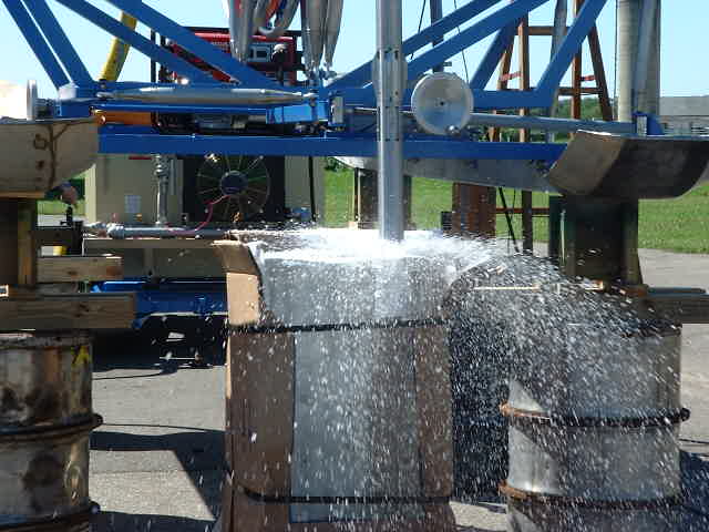 The drill portion being tested on cardboard boxes, with a lot of water spewing out.