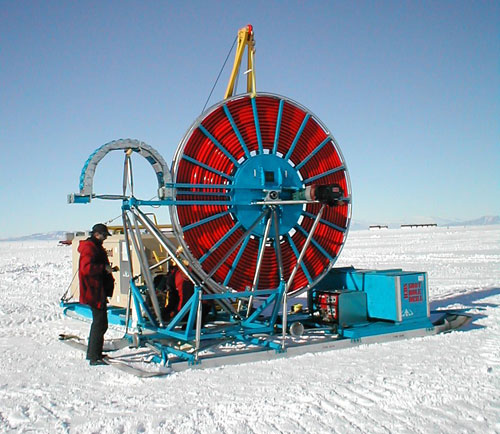 A man in a red jacket standing next to the shot Hole Drill in Antarctica