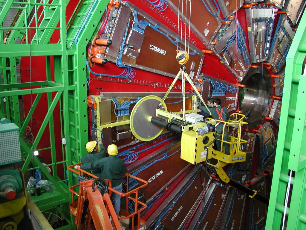 Two people in dark blue jumpsuits observing the inside of the CMS