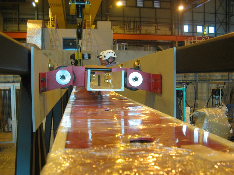 A side image of the DUNE APA being worked on. The two people working on it are wearing white hard hats.